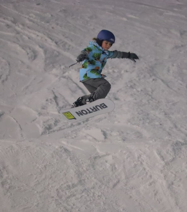 Boarding Millie catching some air on a freestyle snowboard park jump.